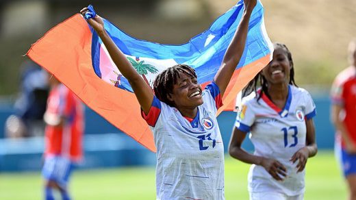 Ruthne Mathurin alza la bandiera di Haiti dopo la vittoria dello spareggio contro il Cile dello scorso inverno.