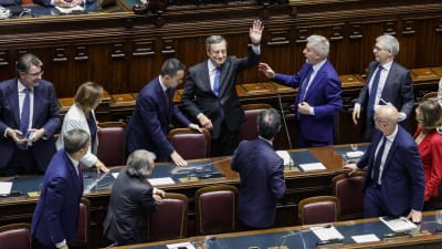 Mario Draghi circondato da altri politici nel Parlamento italiano.
